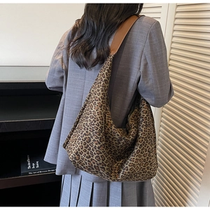 Détail d'un grand sac hobo léopard avec bandoulière en cuir marron porté par un mannequin