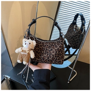 Detail view of leopard print crossbody bag with cute teddy bear charm in a mirror reflection