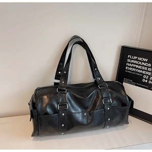 Detail of black faux leather travel bag with silver studs and metal buckles