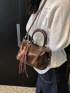 Sac Boston en cuir huilé marron foncé porté en bandoulière pour un style élégant