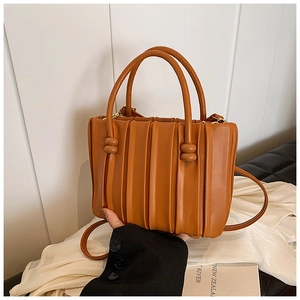 Detail of brown pleated bucket bag showing soft texture and knot handle design