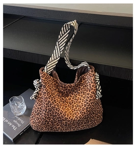 Détail du sac cabas léopard avec bandoulière tissée rayée sur une table minimaliste