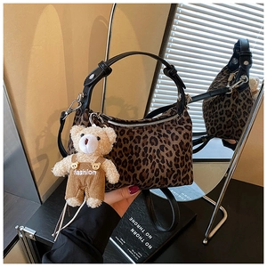 Detailed view of leopard print plush handbag featuring a cute teddy bear charm