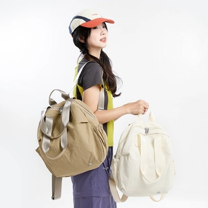 Three lightweight nylon backpacks and a baseball cap shown in a professional studio setting