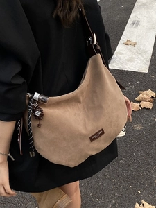 Sac à main kaki en daim style dumpling avec charms vintage en photo de rue urbaine