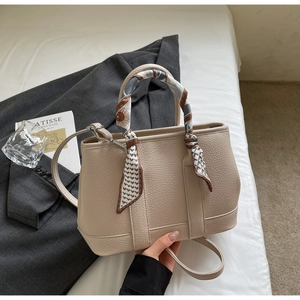 Detail of apricot pebbled leather handbag with geometric silk scarf on the handle