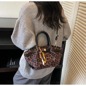 Detail of leopard print handbag with beaded charm and black round handle for women