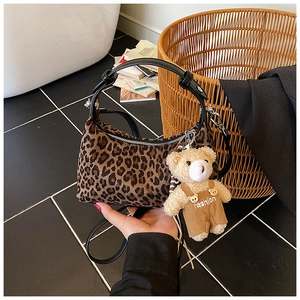 Detail of leopard print handbag with plush bear charm and detachable leather strap