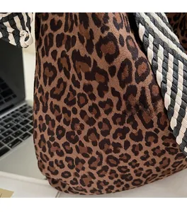 Détail de la texture léopard en daim et de la bandoulière tissée sur ce sac fourre-tout