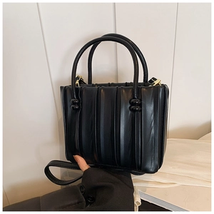 Detail of black pleated leather bucket bag with golden metal hardware and round handles