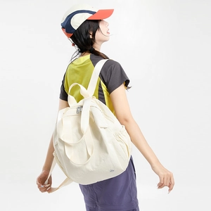 Detail of cream white nylon backpack with drawstring side pocket and sturdy top handle
