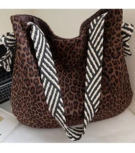 Détail d'un sac cabas léopard avec bandoulière tissée à rayures noires et blanches