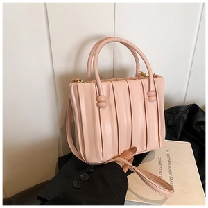 Detail of pink pleated bucket bag with cylindrical handles and gold hardware accents