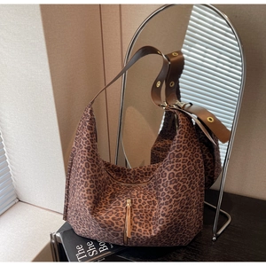 Détail d'un sac cabas léopard avec bandoulière en cuir marron et fermeture éclair en métal