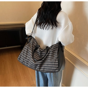 Detail of striped travel tote bag with separate shoe compartment and shoulder strap