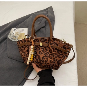 Detail of leopard print bucket bag with wooden bead tassels and leather handle