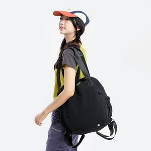 Detail of black waterproof nylon backpack featuring side drawstring pocket and metal logo