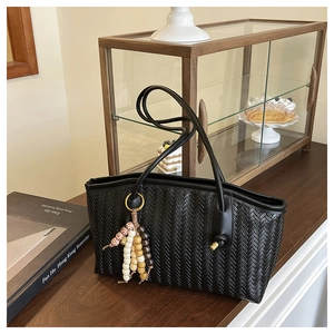 Close-up of black woven tote bag with colorful beaded tassel in a retro setting