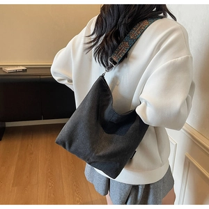 Detail of grey canvas hobo bag with ethnic embroidered wide strap worn by a model