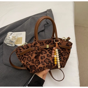 Close-up of leopard print bucket bag featuring vintage bead charm and brown leather straps