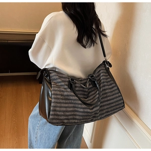 Detail of striped canvas travel duffel bag with leather handles and adjustable shoulder strap