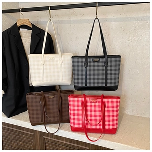 Close-up of elegant plaid tote bags in various colors with metallic logo detail