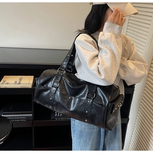 Detailed view of black travel tote with silver metal studs and premium leather texture