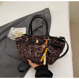 Detail of leopard print bucket bag with round handles and colorful beaded charm accessory