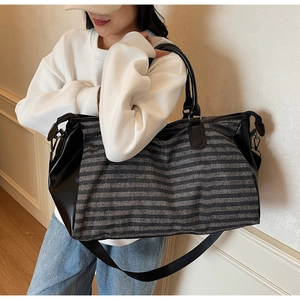 Detail view of striped travel bag with reinforced leather handles and shoulder strap