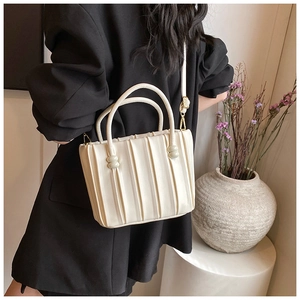 Detail of a pleated off-white bucket bag shown in a professional lifestyle photoshoot
