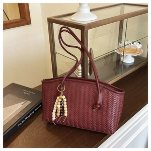 Detail of burgundy woven tote bag with vintage wood bead tassel and V-pattern texture