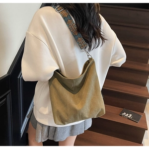 Sac bandoulière en toile vert olive avec large sangle bohème porté par un mannequin