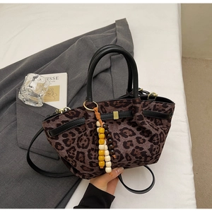 Detail of leopard print bucket bag with wood bead pendant and black leather handles