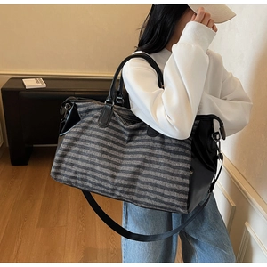 Striped travel tote bag with leather details shown on model for size perspective