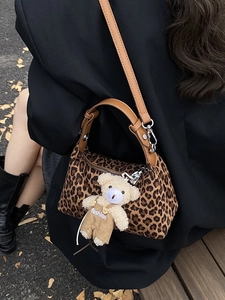 Fashionable leopard print handbag with brown leather straps and a plush bear pendant
