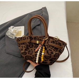 Close-up of leopard print bucket bag with brown leather handles and colorful beaded tassels