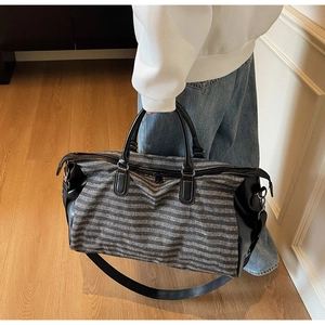 Spacious striped travel tote bag featuring black leather handles and durable shoulder strap