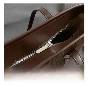 Close-up of premium silver metal zipper and reinforced stitching on a brown tote bag