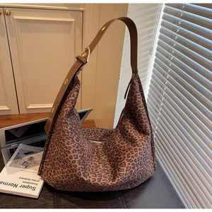 Détail de la bandoulière réglable avec œillets dorés sur le sac fourre-tout léopard