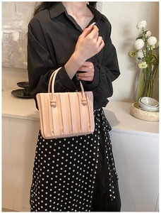 Macro shot of pale pink pleated bucket bag with vertical textures and rounded handle details