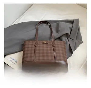 Detail of vintage brown plaid tote bag with leather trim and gold metal logo plaque