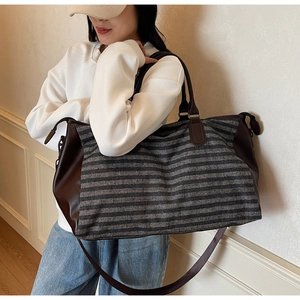 Macro detail of striped travel bag featuring premium leather handles and shoulder strap