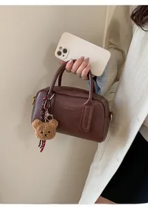 Dettaglio borsa bowling in pelle marrone vintage con un grazioso ciondolo a orsetto