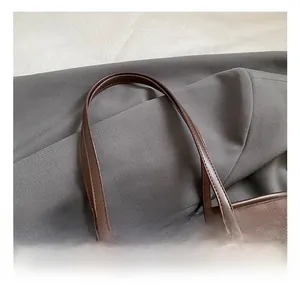 Detail view of durable brown tote handles with precise stitching and textured leather finish