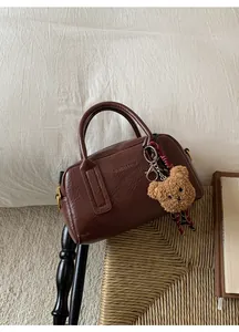 Dettaglio di una borsa Boston marrone scuro in ecopelle con ciondolo a orso e sciarpa di seta