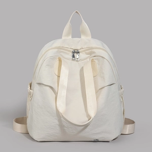 Detail view of cream nylon backpack featuring dual metal zippers and side drawstring pockets