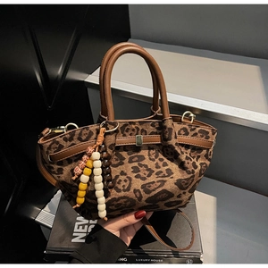 Detail of leopard print bucket bag with leather handles and decorative beaded pendant