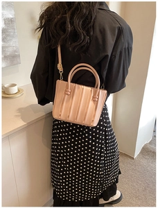 Rear view of model wearing a dusty pink pleated bucket bag with a floral midi skirt