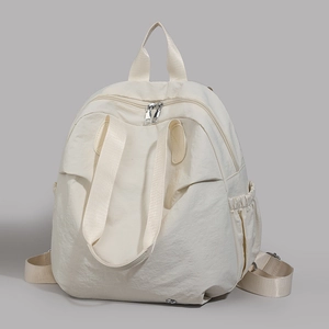 Detailed view of cream nylon backpack with zippered main compartment and side pockets