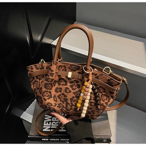 Detail of leopard print bucket bag with brown leather handles and beaded charm pendant